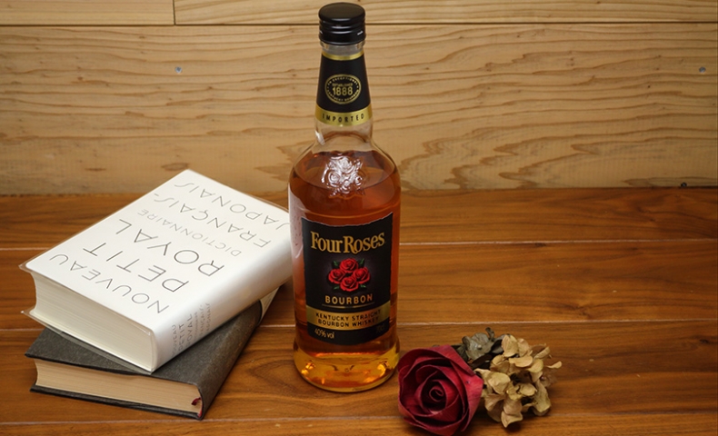ウイスキーのボトルと本とバラの造花